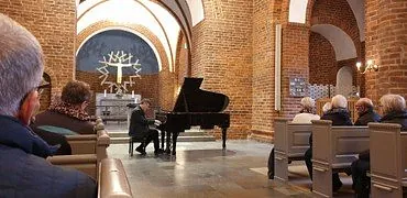 Billede af Nicolai der spiller på flygel i midten af kirken