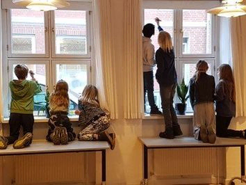 Billede af børn der tegner på vinduerne i sognehuset