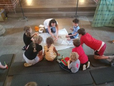 Billede af Kirsten der fortæller fadervor med sand omringet af børn