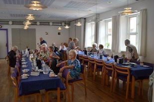 Billede af ffredagsÅben deltagere ved bordene i sognehuset