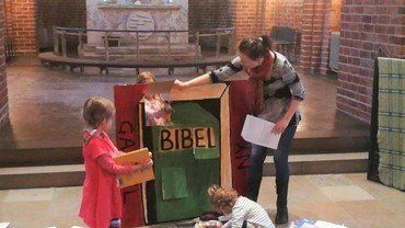 Billede af Kirsten med den store lege bibel og et barn
